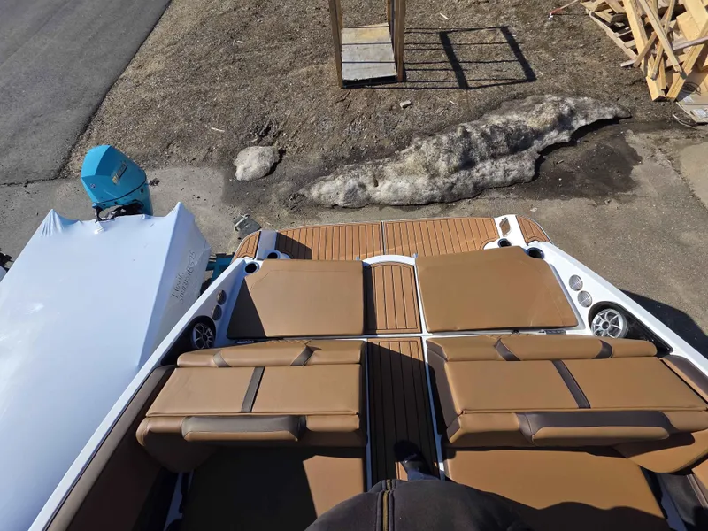 Slide: The Image of 2025 Yamaha Boats 222SE with tan seating and teak-style deck, parked outdoors. - 15