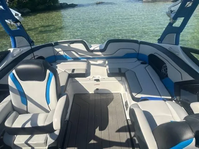 Slide: The Image of 2019 Yamaha Boats 212X interior with blue and white seating, near clear water. - 7