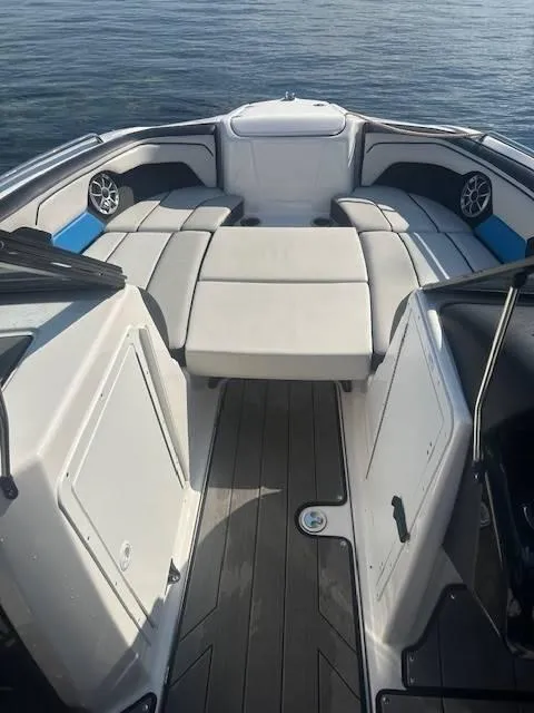 Slide: The Image of 2019 Yamaha Boats 212X interior with cushioned seating and sleek design on calm water. - 9