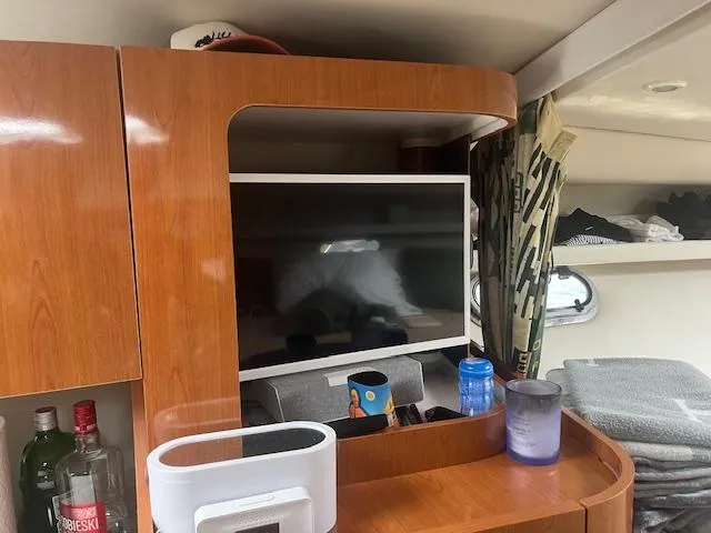 Slide: The Image of Interior of 2000 Four Winns 328 Vista boat with TV, shelves, and wooden cabinetry. - 24