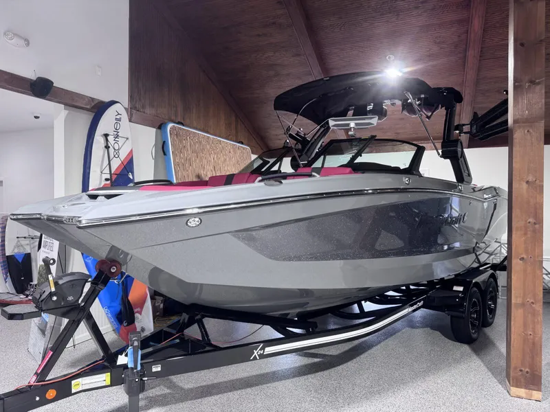 The Image of 2025 MasterCraft X24 boat in garage, sleek gray design on trailer. - 0