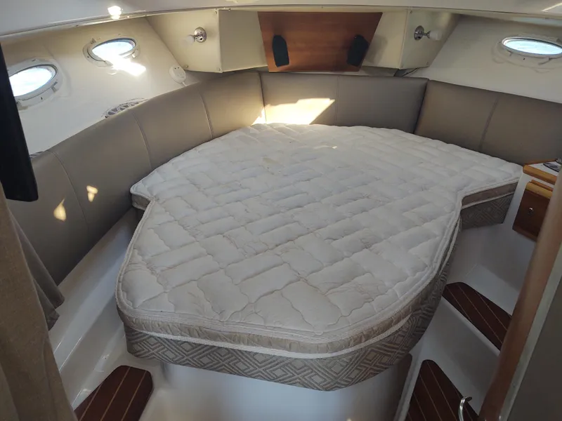 Slide: The Image of 2018 Cutwater C-302 Coupe interior cabin with a cozy bed and porthole windows. - 44