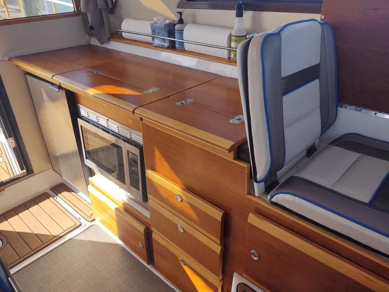 Slide: The Image of 2018 Cutwater C-302 Coupe interior with wood cabinetry, seating, and built-in microwave. - 45