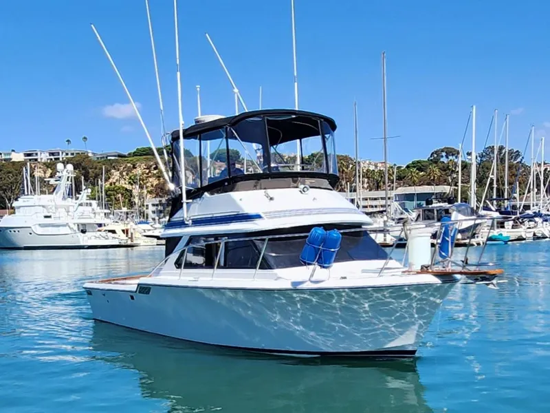 The Image of 1988 Chris-Craft 315 Commander boat docked in a marina under clear blue skies. - 0