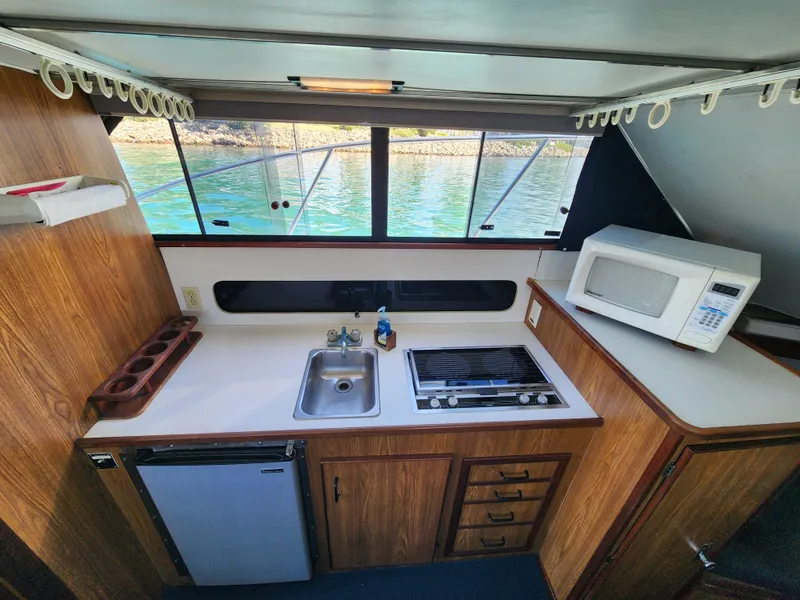 Slide: The Image of 1988 Chris-Craft 315 Commander boat kitchen with sink, stove, fridge, and microwave. - 29