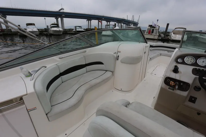 Slide: The Image of 2002 Chaparral 280 SSi boat interior with seating and dashboard, docked near a bridge. - 21