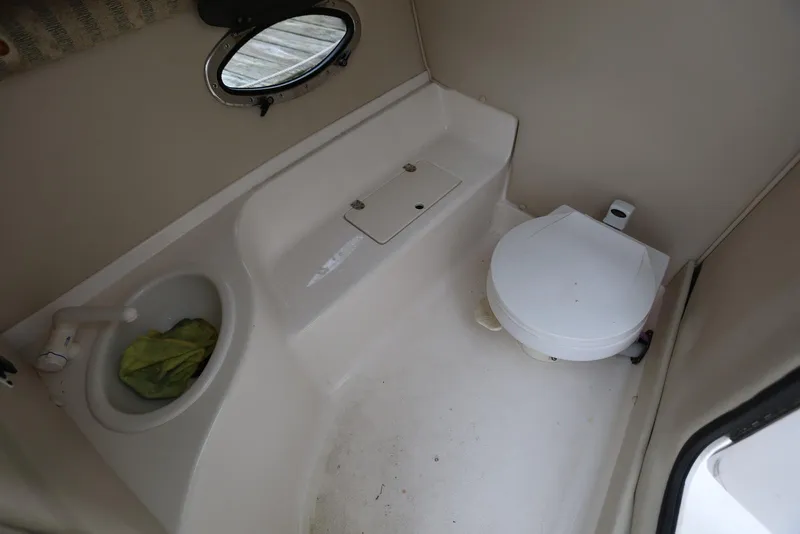 Slide: The Image of 2002 Chaparral 280 SSi boat bathroom with sink, toilet, and porthole window. - 25