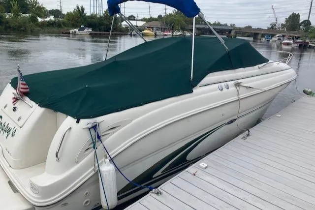 Slide: The Image of 2001 Sea Ray 245 Weekender boat docked with green cover, calm water background. - 1