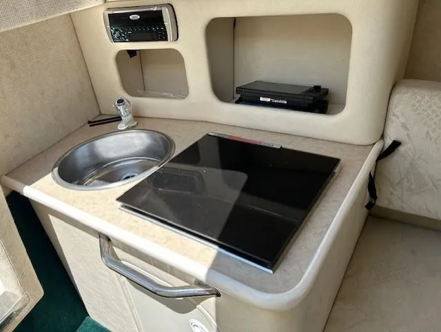 Slide: The Image of 2001 Sea Ray 245 Weekender cabin kitchenette with sink and stove. - 11
