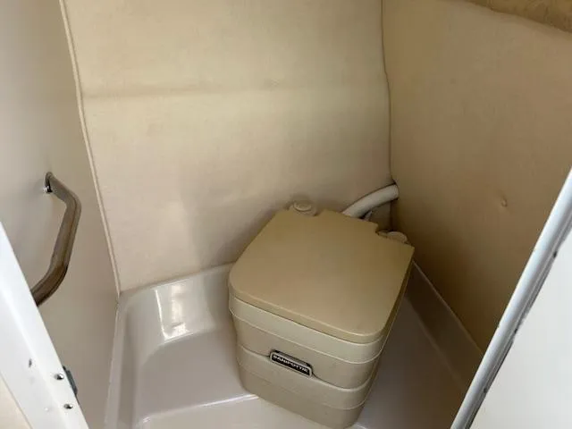 Slide: The Image of 2001 Sea Ray 245 Weekender boat interior with portable toilet in compact bathroom. - 12