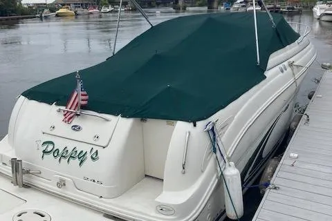 Slide: The Image of 2001 Sea Ray 245 Weekender boat docked, covered with a green tarp, displaying an American flag. - 2