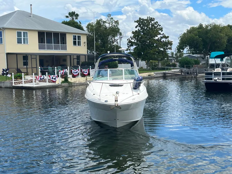 Slide: The Image of 2005 Sea Ray Sundancer 260 boat on calm water near a house. - 4