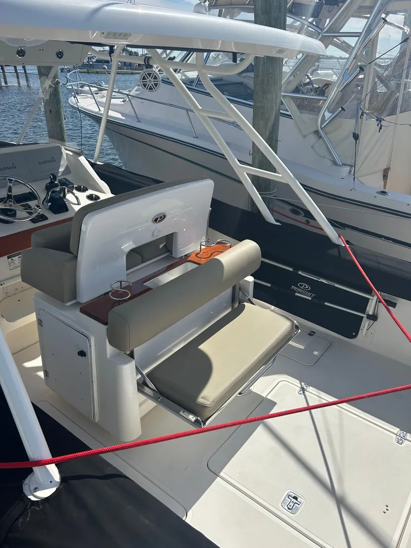 Slide: The Image of 2016 Pursuit S 280 Sport boat interior with seating and helm, docked at marina. - 17