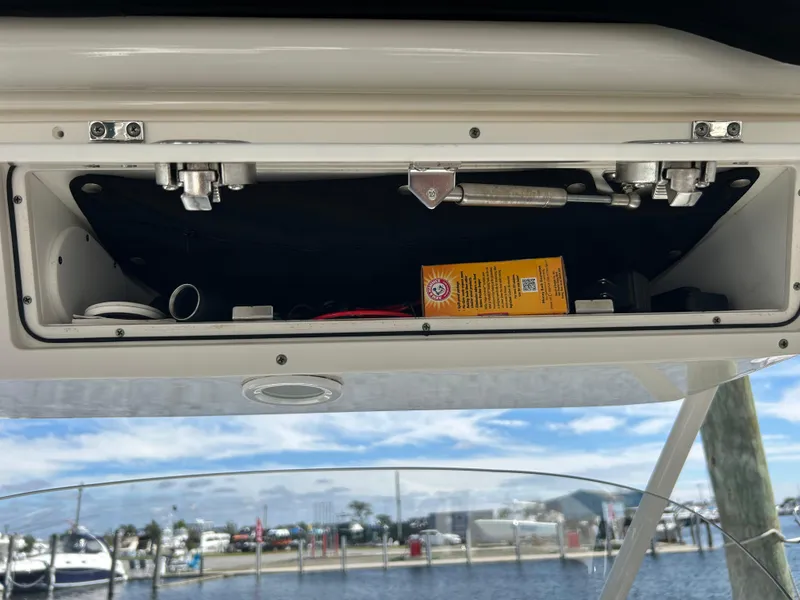 Slide: The Image of Open storage compartment on 2016 Pursuit S 280 Sport boat, with marina view. - 35