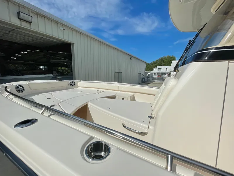 Slide: The Image of 2025 Grady-White 281 Coastal Explorer boat deck with seating, docked near a warehouse. - 8