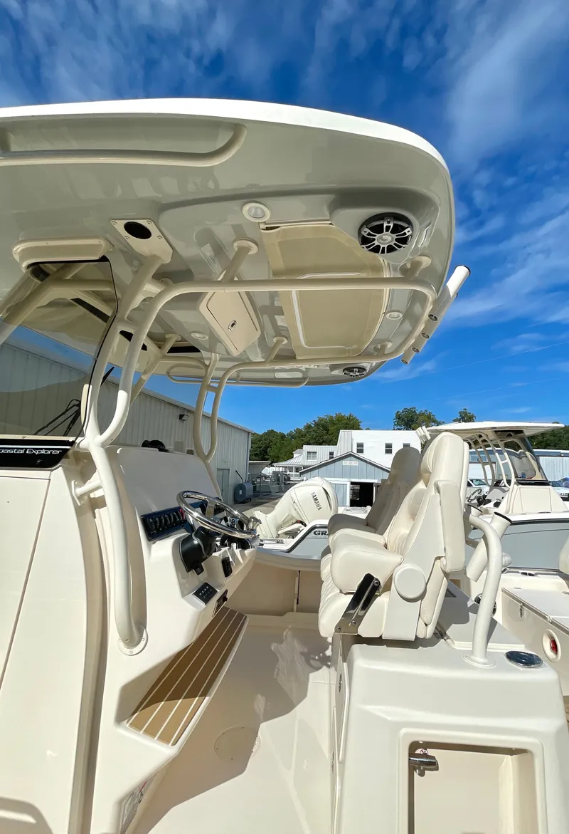 Slide: The Image of 2025 Grady-White 281 Coastal Explorer boat interior with helm and seating under blue sky. - 9