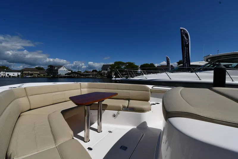 Slide: The Image of 2019 Pursuit S 408 Sport boat with beige seating and table, docked under clear blue sky. - 41