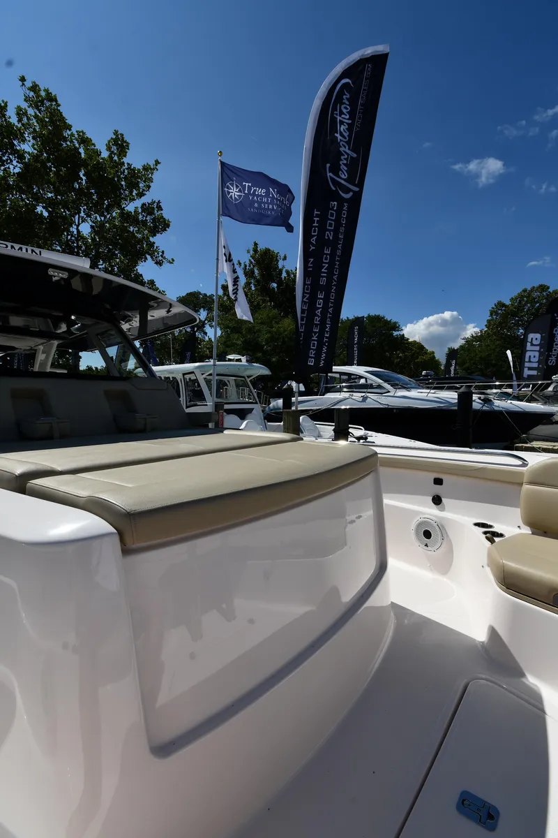 Slide: The Image of 2019 Pursuit S 408 Sport boat at a marina with flags and trees. - 46