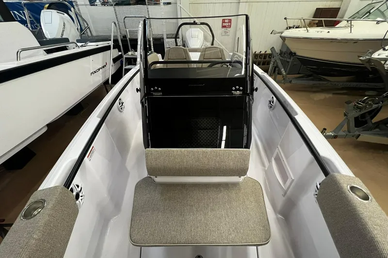 Slide: The Image of 2025 Axopar 22 Spyder boat interior with seating and console, displayed in showroom. - 15