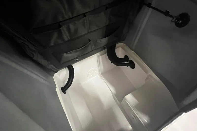 Slide: The Image of 2025 Axopar 22 Spyder interior storage compartment with black fabric and ventilation hoses. - 17