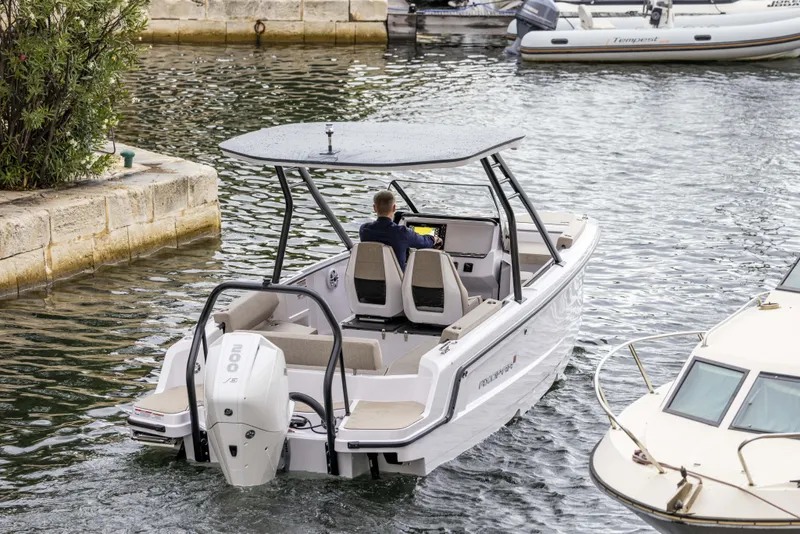 Slide: The Image of 2025 Axopar 22 Spyder interior with seating and table, displayed in a showroom. - 3