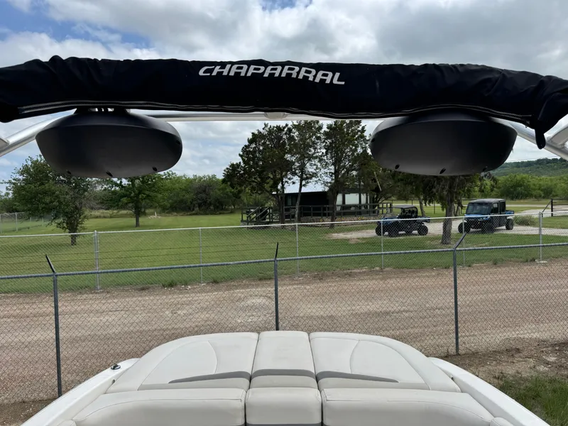 Slide: The Image of 2007 Chaparral 236 SSi boat with speakers, parked near a fenced grassy area. - 10