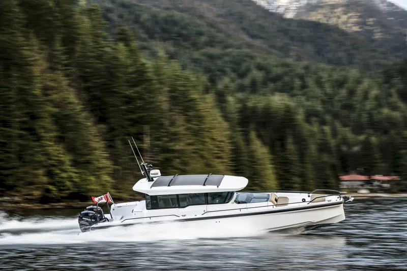 Slide: The Image of 2025 Axopar 37 XC CROSS CABIN cruising on a scenic lake with forested hills. - 12