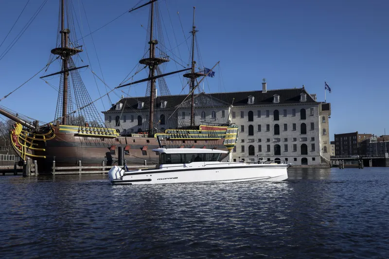 Slide: The Image of 2025 Axopar 37 XC CROSS CABIN boat on water near historic ships and buildings. - 14
