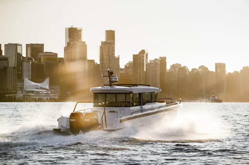 Slide: The Image of 2025 Axopar 37 XC CROSS CABIN cruising on water with city skyline backdrop. - 15