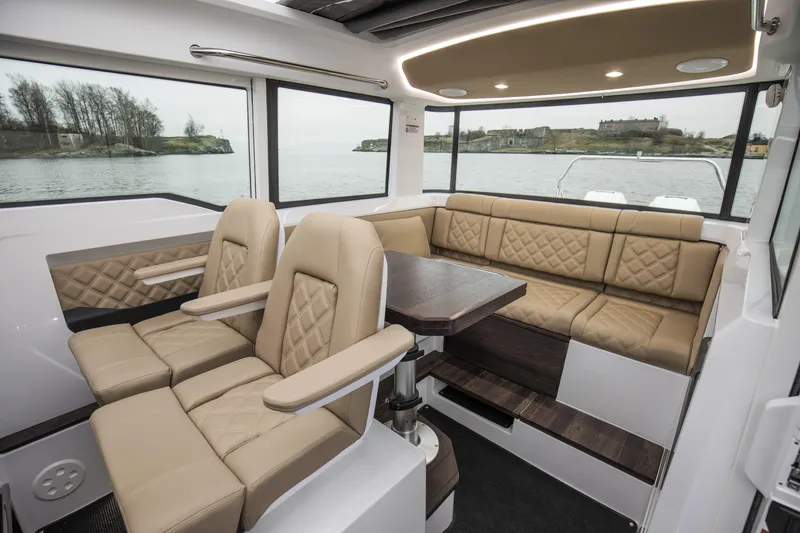 Slide: The Image of Luxurious interior of 2025 Axopar 37 XC CROSS CABIN with beige seating and panoramic windows. - 24
