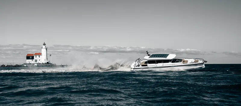 Slide: The Image of 2025 Axopar 37 XC CROSS CABIN cruising near a lighthouse on open water. - 3