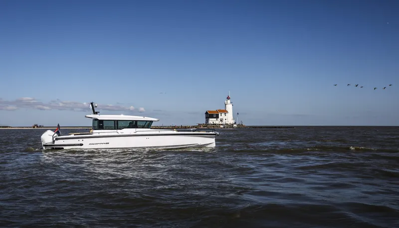 Slide: The Image of 2025 Axopar 37 XC CROSS CABIN boat near a lighthouse on a sunny day. - 6