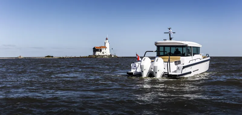 Slide: The Image of 2025 Axopar 37 XC CROSS CABIN boat cruising near a lighthouse on open water. - 7