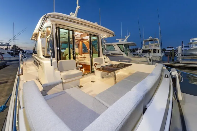 Slide: The Image of 2026 Sabre 43 Salon Express yacht with elegant seating and table at sunset in marina. - 11