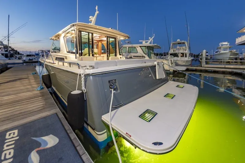 Slide: The Image of 2026 Sabre 43 Salon Express yacht docked at marina, illuminated underwater lights. - 10