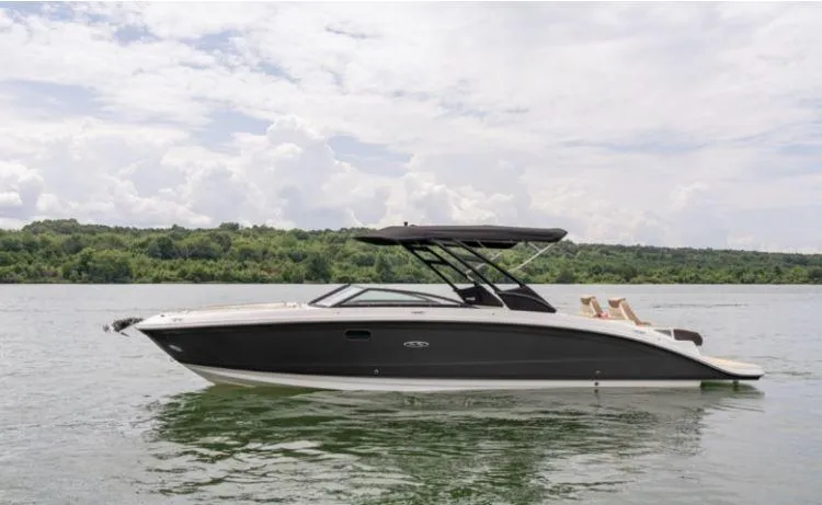 Slide: The Image of 2025 Sea Ray SDX 290 boat on a calm lake with lush green shoreline. - 14