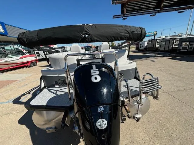 Slide: The Image of 2024 Harris Sunliner 230 CWDH pontoon boat with 150 HP engine, docked outdoors. - 20