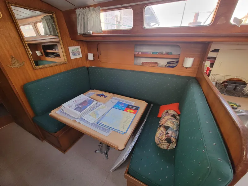 Slide: The Image of Cozy 1967 Spencer 42 yacht interior with green seating, table, and nautical decor. - 23