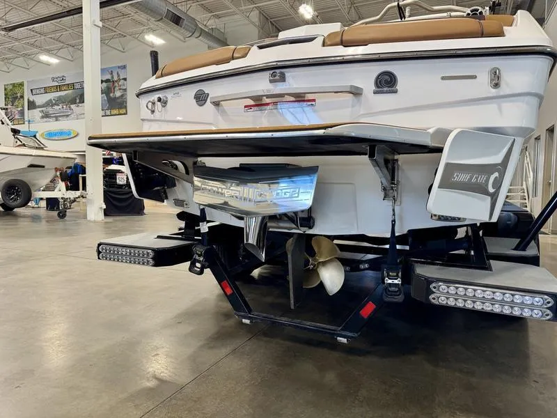 Slide: The Image of 2021 Malibu 25 LSV boat rear view in showroom, showcasing propeller and swim platform. - 10