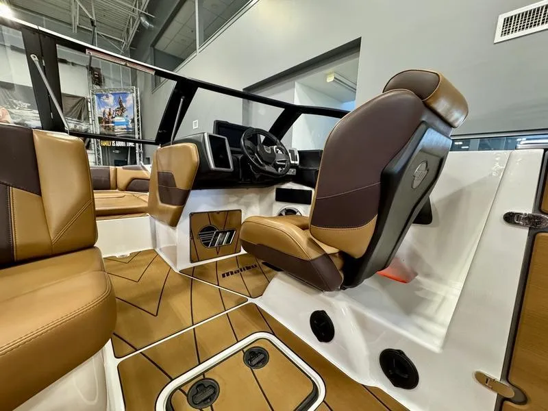 Slide: The Image of 2021 Malibu 25 LSV boat interior with brown leather seats and modern dashboard. - 12