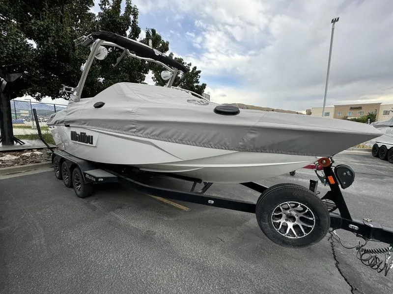 Slide: The Image of 2021 Malibu 25 LSV boat on trailer, covered, parked outdoors. - 18