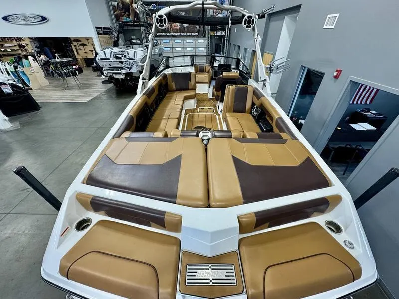 Slide: The Image of 2021 Malibu 25 LSV boat interior with tan and brown seating in showroom. - 9