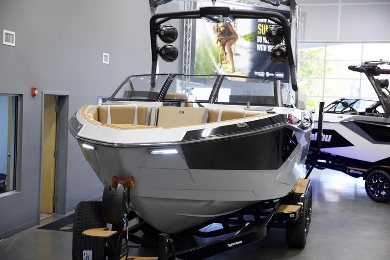 Slide: The Image of 2025 Malibu 26 LSV boat displayed indoors on a trailer. - 10