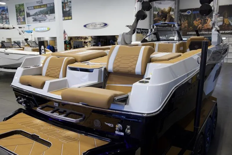 Slide: The Image of 2025 Malibu 26 LSV boat with luxurious tan seating in showroom. - 11