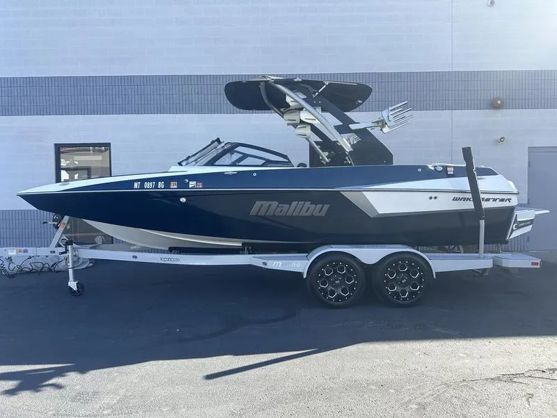 Slide: The Image of 2020 Malibu 22 MXZ boat on trailer, parked outdoors. - 1