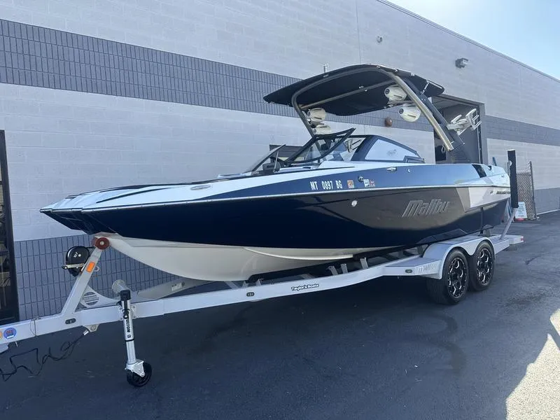 Slide: The Image of 2020 Malibu 22 MXZ boat on trailer, parked outside a building. - 3
