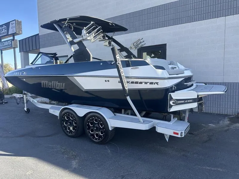 Slide: The Image of 2020 Malibu 22 MXZ boat on trailer, parked outside a building. - 4