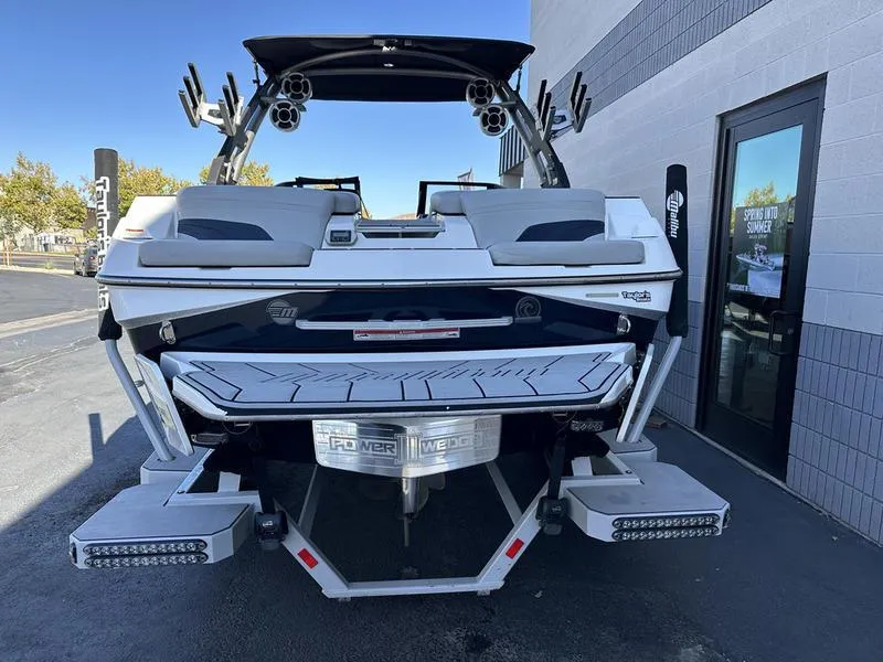 Slide: The Image of 2020 Malibu 22 MXZ boat, rear view, parked near a building. - 7