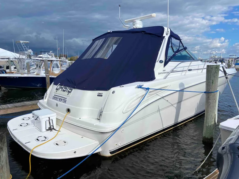 Slide: The Image of 2002 Sea Ray 380 Sundancer docked at marina, featuring blue canvas cover. - 1