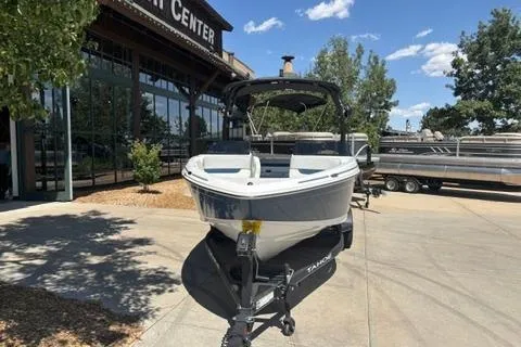 Slide: The Image of 2024 Tahoe 210 Si Limited boat on trailer outside dealership, sunny day. - 2